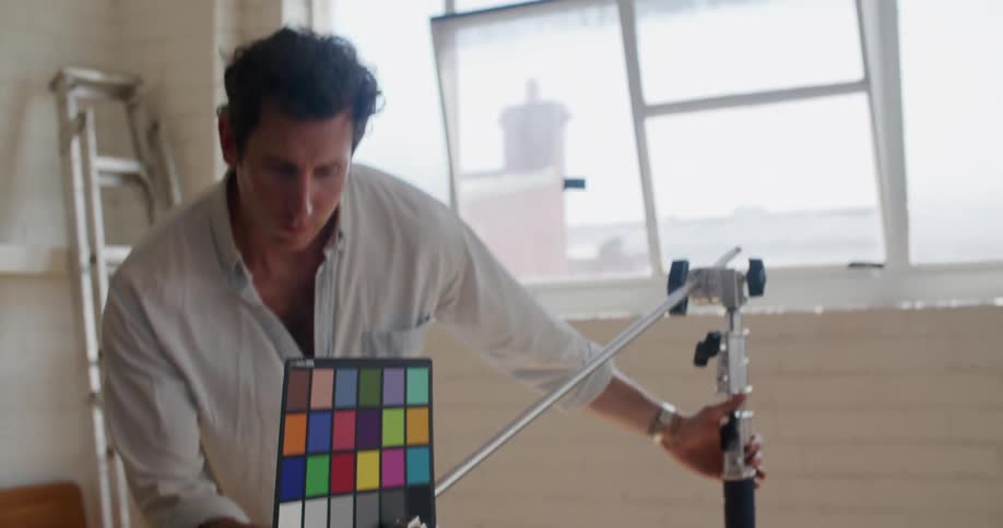 Filmmaker working on a room adjusts a color checker palette in front of the camera