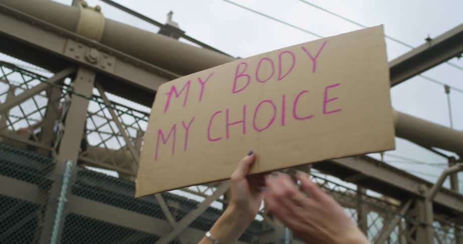 A woman is holding up a sign at an rally my body my choice