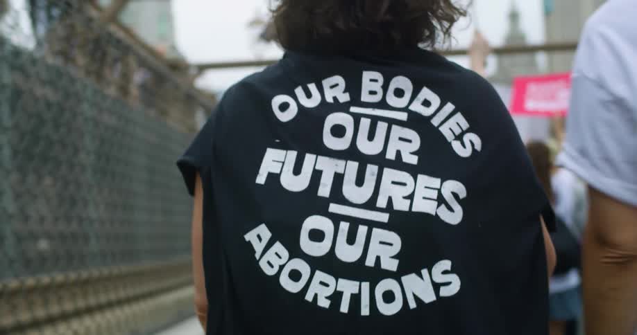 A woman is walking with other women in a pro protest with a pro shirt on her back