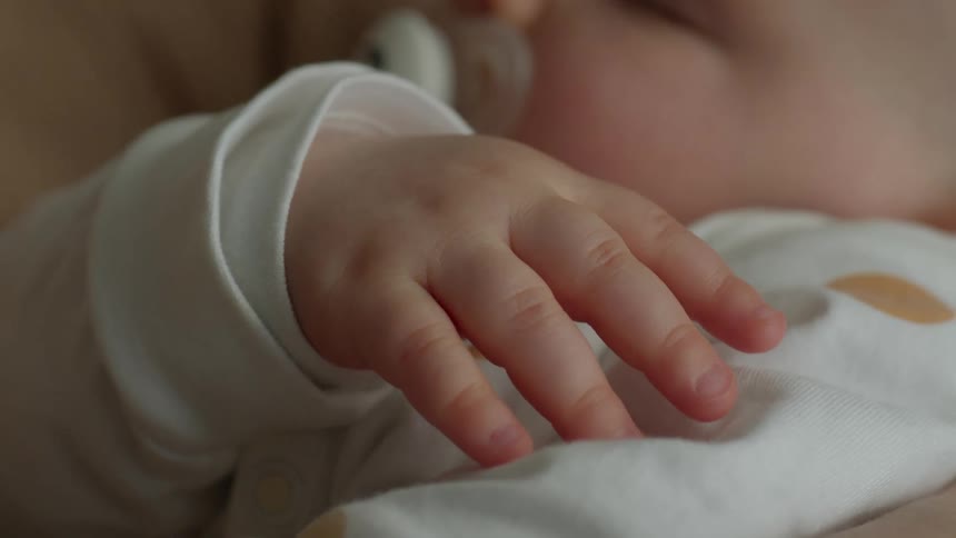 Close up of a newborn baby sucking on a soother and sleeping