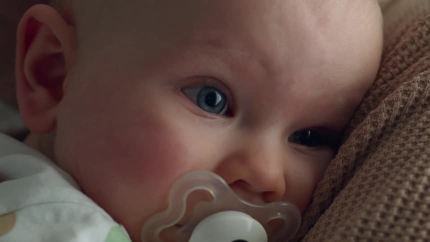 Mom sways holding baby with his head on her shoulder when he turns his head toward her