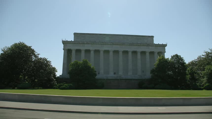 Automobiles travel on the road in front of the lincoln memorial