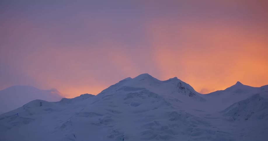 Snow covered mountains with peaks high in a red sky