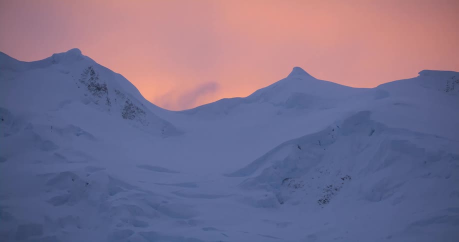 The sky is red as the sun sets on the mountain
