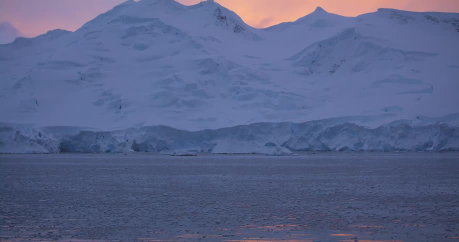 The snow covered mountains are by the shore