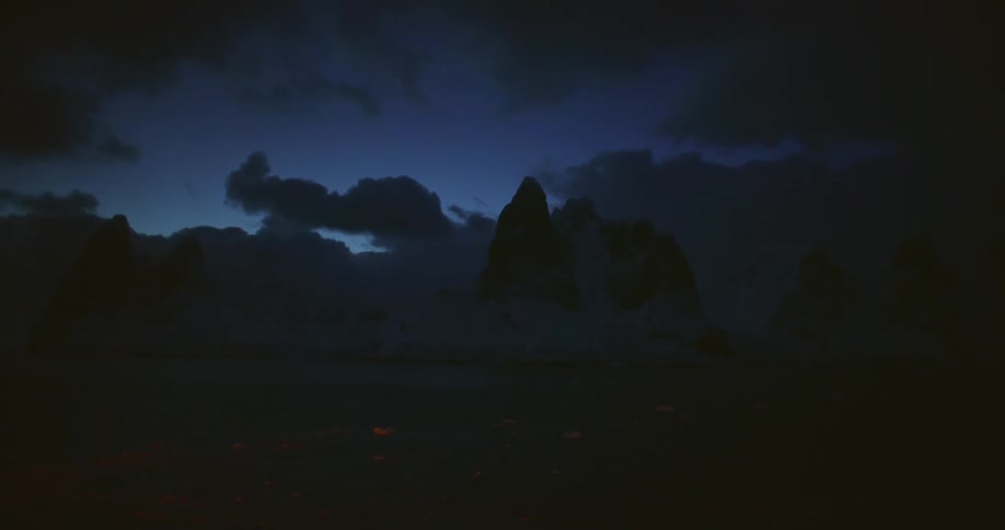 Night falls over the arctic mountains next to the ocean