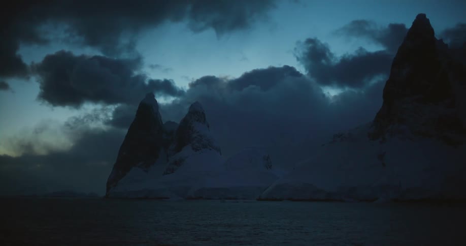 Icebergs are floating in the water under a cloudy sky