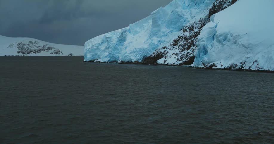 Aerial view of a mountain covered by a thick layer of snow and ice next to the ocean