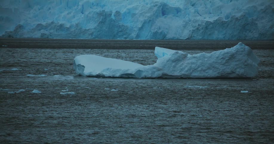 Pieces of ice are moving in the water near a glacier