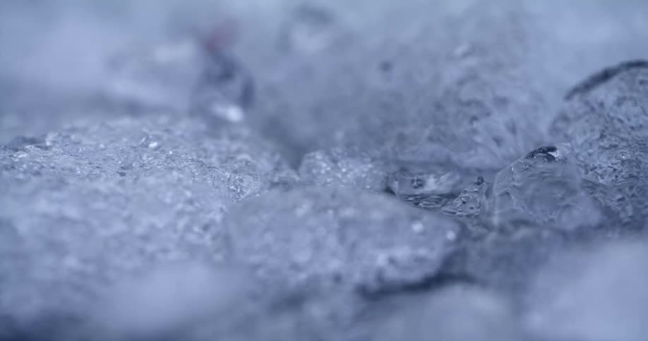 The sun reflects light on pieces of ice floating on the water