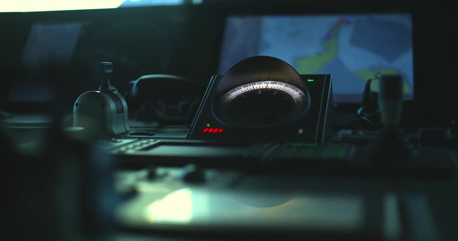 A radar screen is flashing in a dimly lit room and the light of a compass glows in the darkness