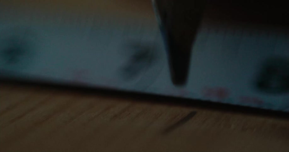 A pencil makes a mark on wood next to a sheet of printed paper