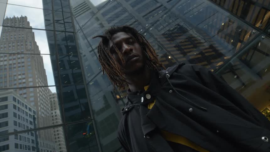 A man stands downtown and looks up at tall skyscrapers