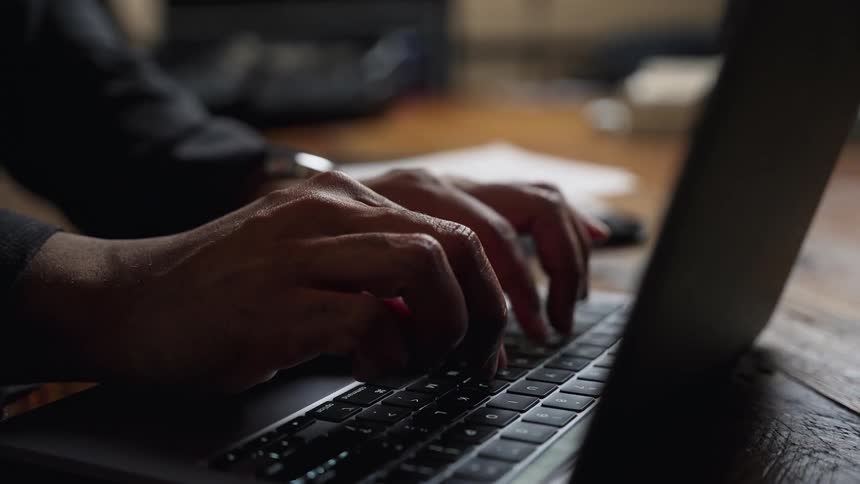 A man typing on a laptop while sitting in an office conference room