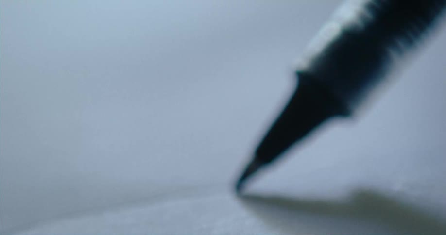 A pen without ink is leaving an impression on paper as it moves
