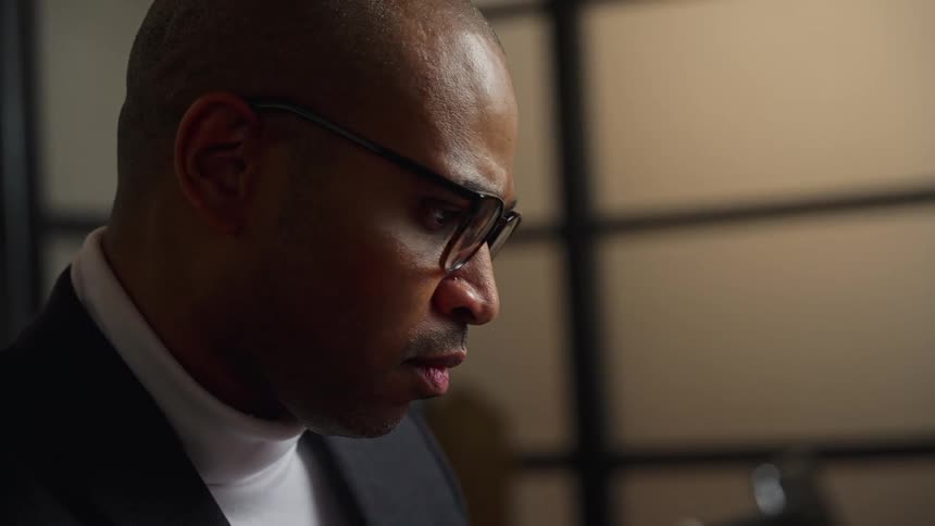 A man puts his glasses on as he concentrates