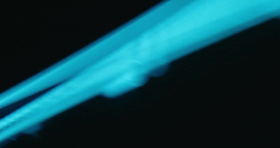 A light blue light shines across the darkness and changes colors to darker blue and red