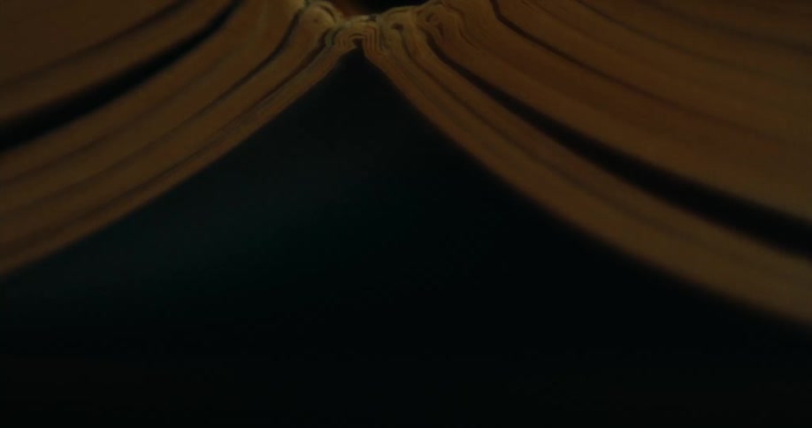 A light blue light shines under two rounded objects in the darkness