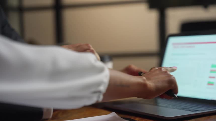 A man and woman in an office talk as they look at a laptop