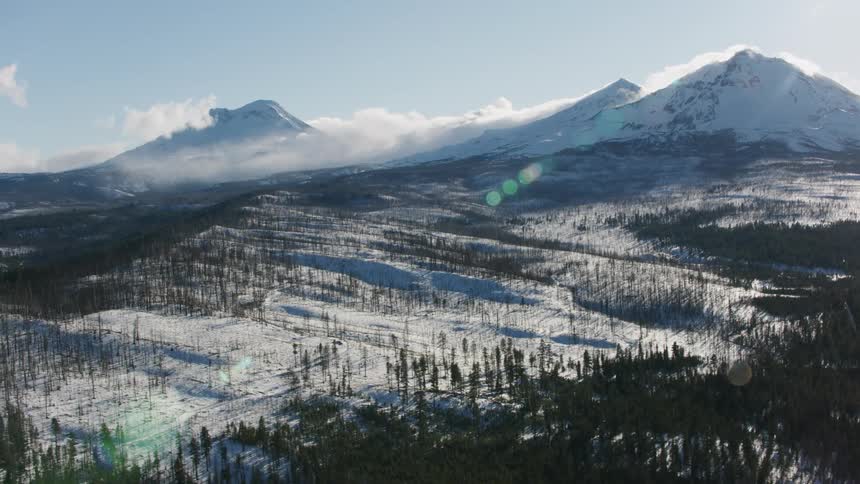 An aerial view of a snow covered mountain range and forest