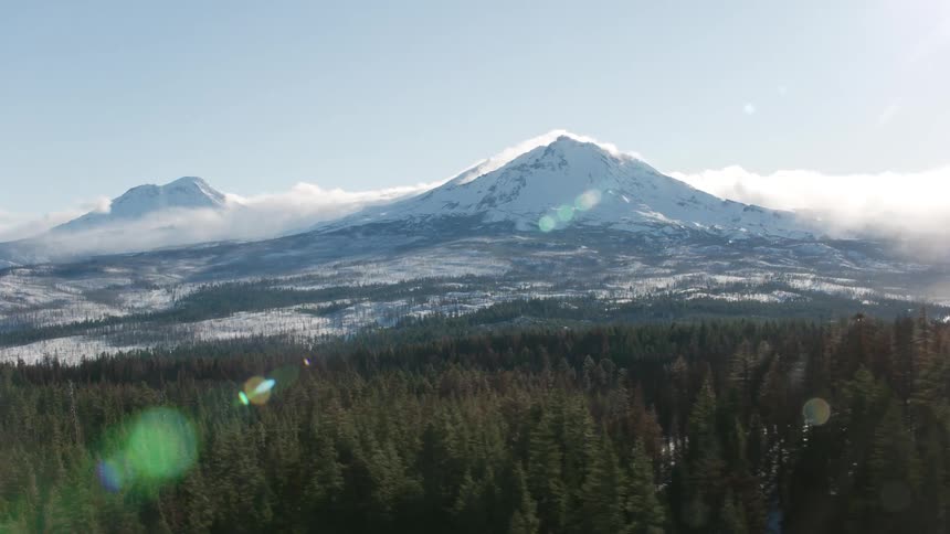 An aerial view of snow covered forest and mountain range
