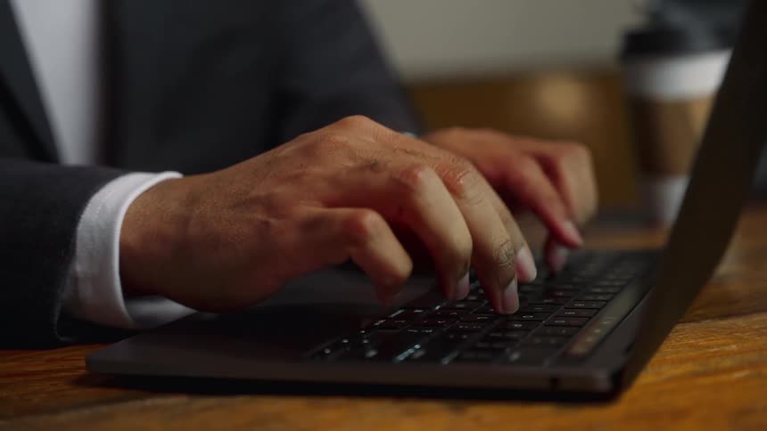 A man sitting in an office conference room typing on a laptop