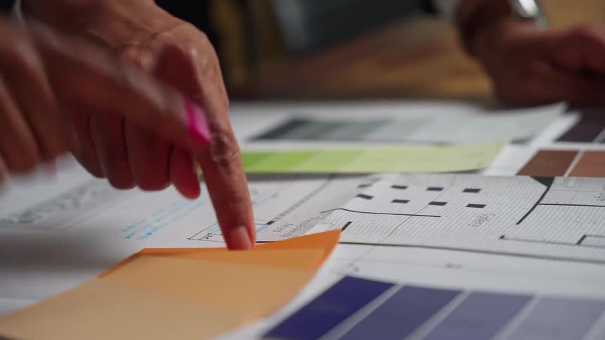 Two people work together to plan the interior design of a workspace using a paper floor plan