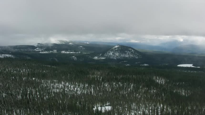 Heavy fog moves over a snow covered forest neara mountain range