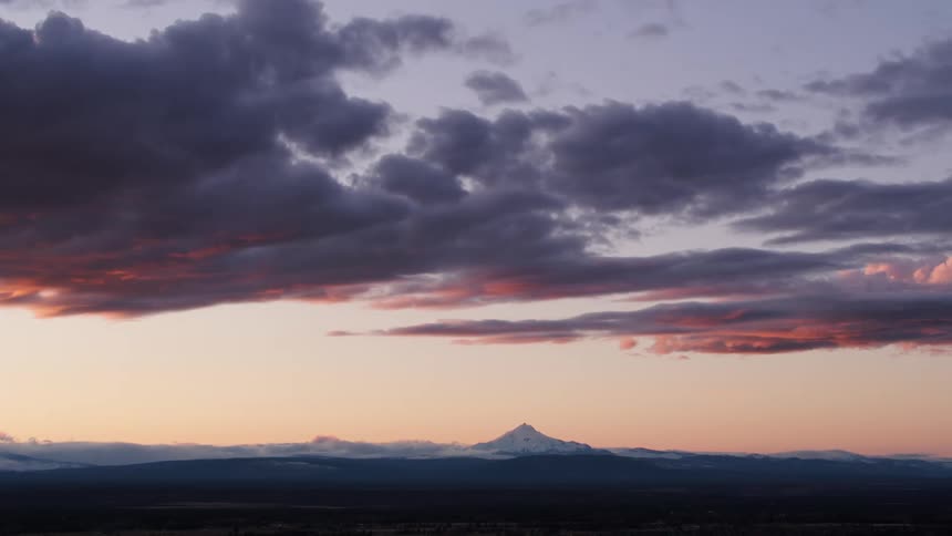Sky and lower layers of clouds shine red over snowy mountains on horizon