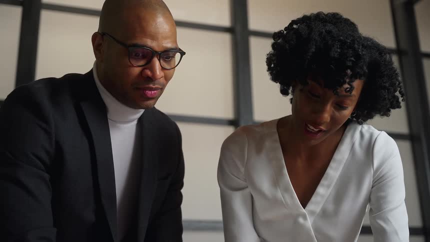A man and woman chat while standing in a conference room