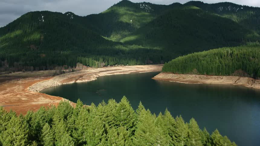 Small patches of snow are visible in the lush green hills above the smooth lake