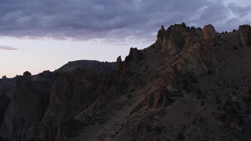 A rocky mountain ridge reaches high in a cloudy sky
