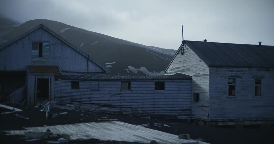 An old dilapidated wooden farm building sits under a cloudy sky