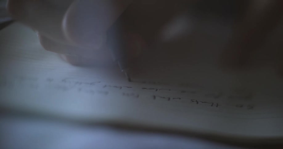 A person is writing in the notebook