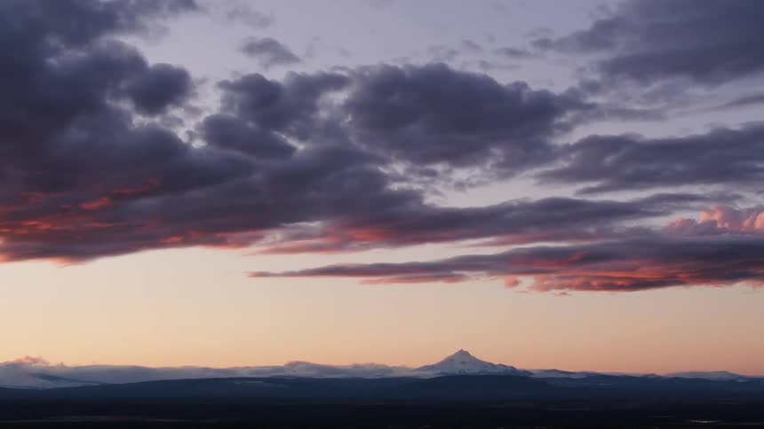Mountains peak on the horizon under a colorful cloudy sky