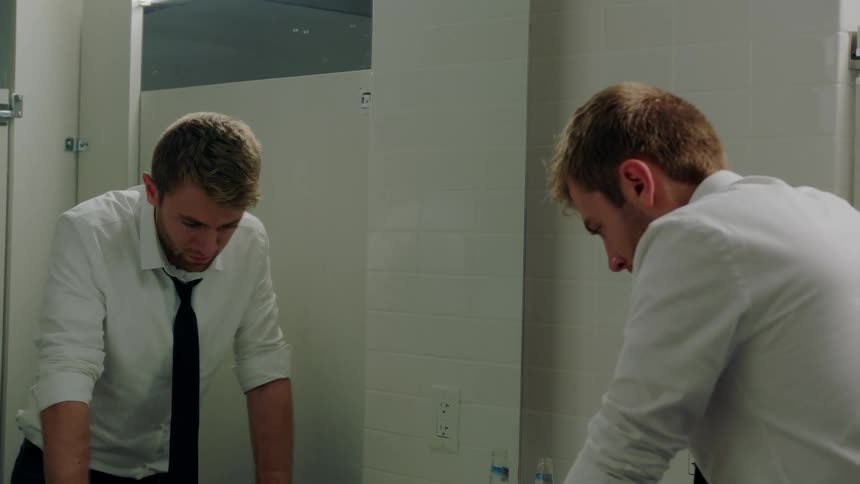 A man is looking at his reflection in a bathroom mirror