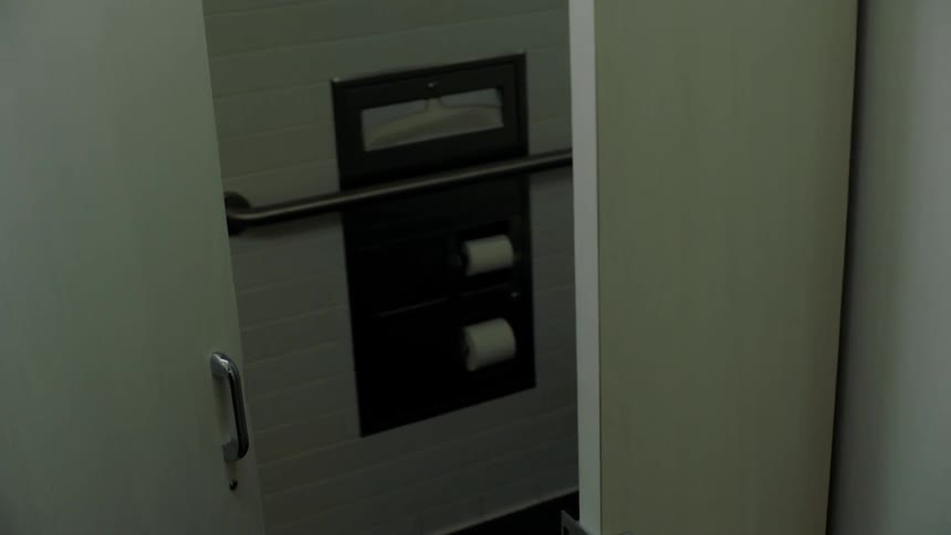 A man pushes the door to a bathroom stall open making sure it is empty