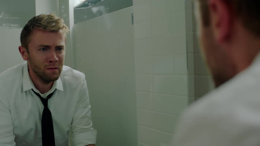 A man is upset and angry while looking at his reflection in a mirror