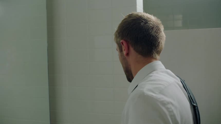A man wipes his face in the bathroom