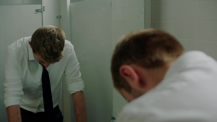 A man leans by the mirror in the bathroom