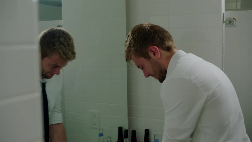 A man is looking at himself in a bathroom mirror
