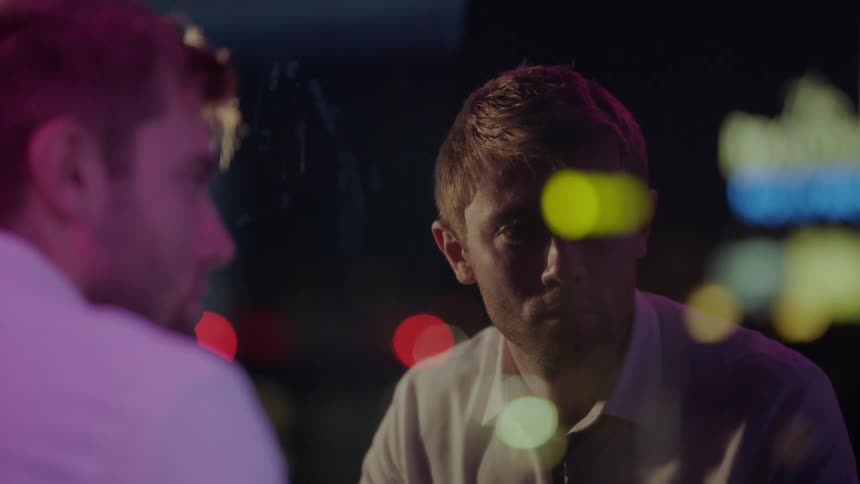 A man sitting at a window at night wearing a shirt and tie looking sad gets up and leaves