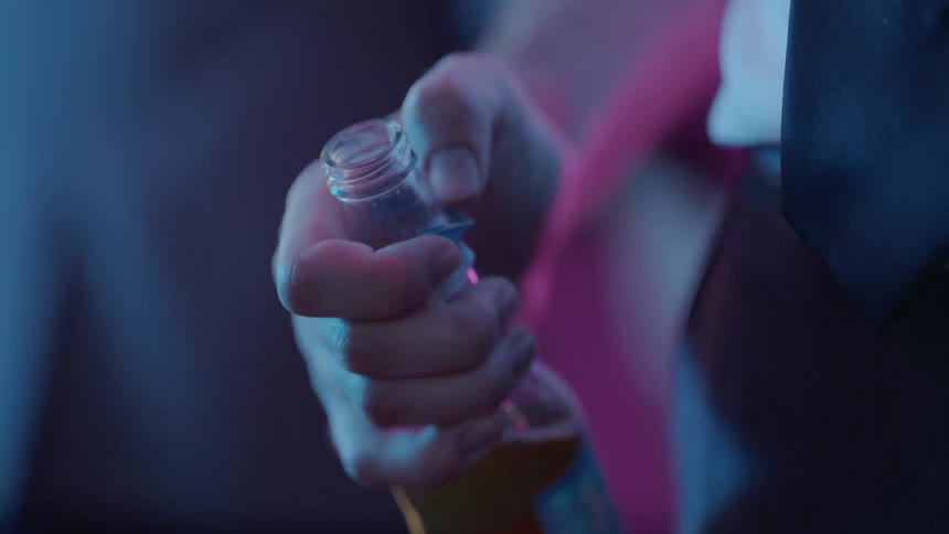 A man holds a beer bottle while nervously scratching at its label with his finger