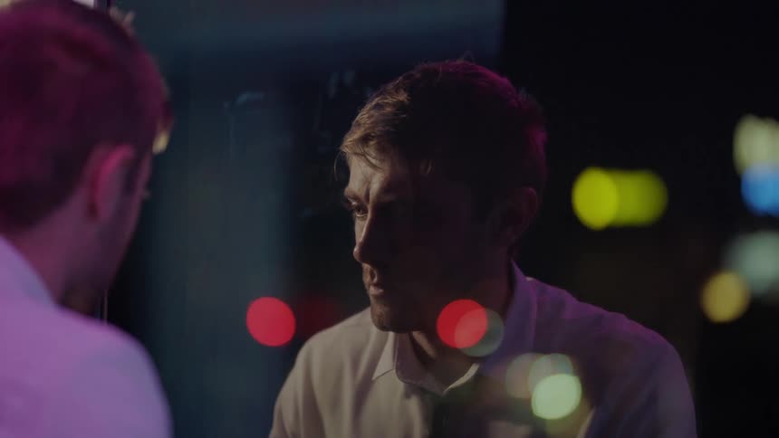 A man looks upset as he looks in a mirror