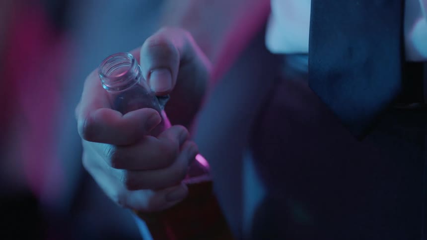 Someone is holding a beer bottle and moving their thumb across the glass