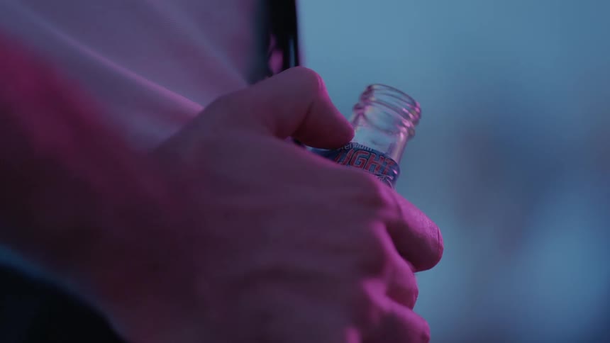 Someone is holding a beer bottle and moving their thumb across the glass