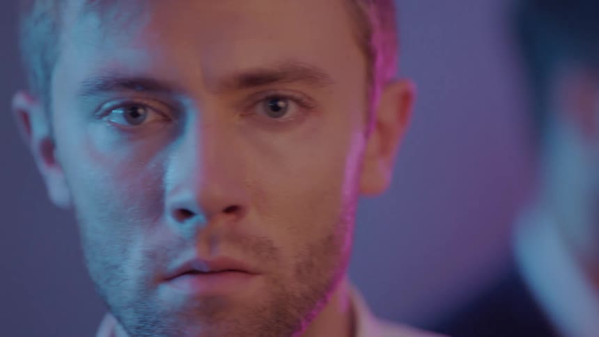 Man stares as people move around behind him in club