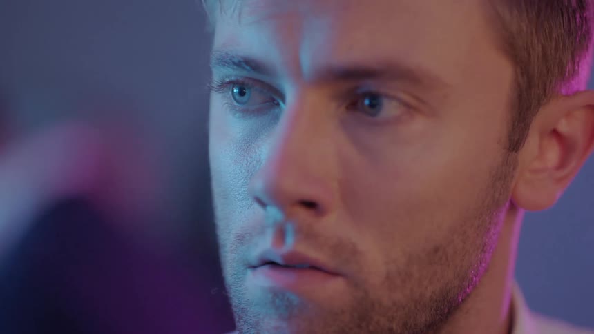 Man stands under colored lighting and looks around during party