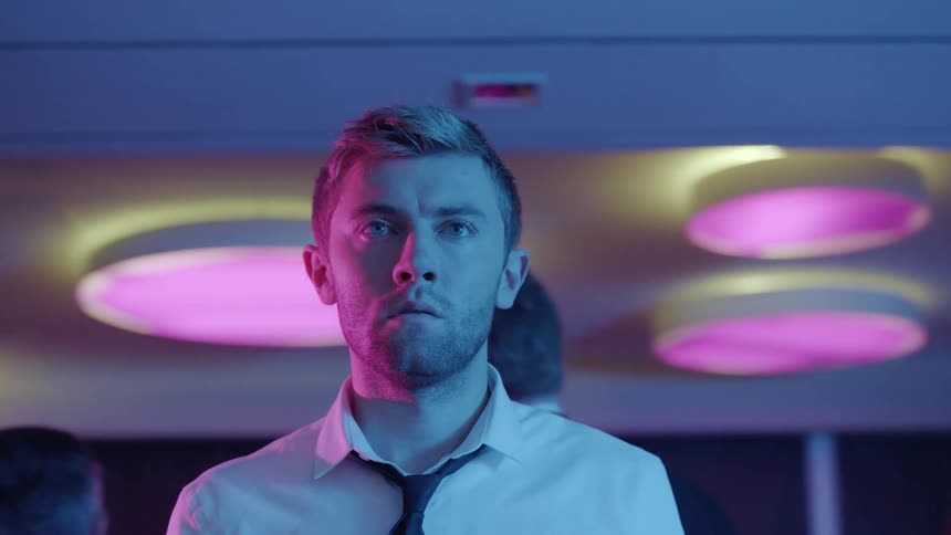 A man is standing in a room blinking