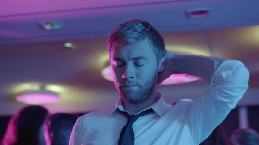 A man is standing at a party with a group of people around